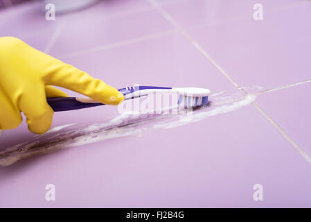 Pulire le piastrelle con uno spazzolino da denti. Foto Stock