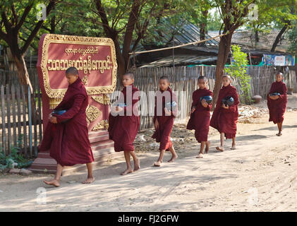 Giovani monaci portano la loro offerta bocce a un tempio - BAGAN, MYANMAR Foto Stock