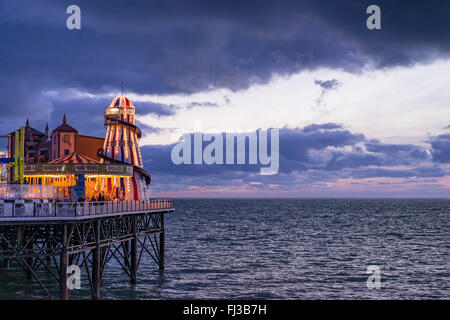 Una vista dalla riva del mare e del divertimento sulla fine di Brighton il Palace Pier prese al tramonto Foto Stock