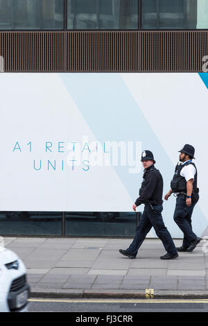 Due poliziotti della polizia, della Metropolitan Police Service a piedi lungo il Victoria Street, Westminster, London, Regno Unito. Foto Stock