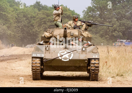 La seconda guerra mondiale la rievocazione. American medie serbatoio, M18 Hellcat, con supporto di fanteria, avanzante attraverso erba alta verso viewer durante la battaglia. Foto Stock