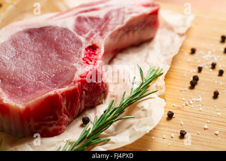 Pezzi di carne cruda con rosmarino e spezie Foto Stock