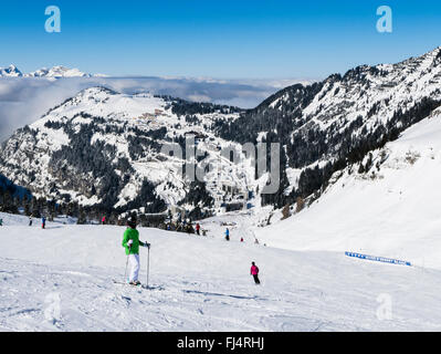 Gli sciatori sulle piste innevate in Le Grand Massif ski area sopra lo sci alpino resort di Flaine, Haute Savoie, Rhone-Alpes, Francia Foto Stock