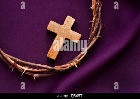 Alta angolazione del legno di un croce cristiana e la corona di spine di Gesù Cristo su un drappo di porpora Foto Stock