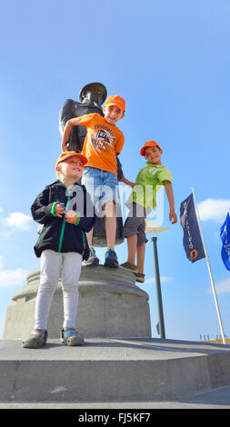 Tre ragazzi arrampicate ad una statua Foto Stock