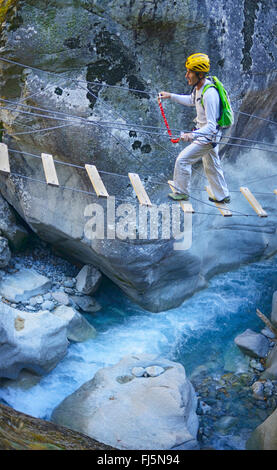 Uomo sulla passerella di sospensione della via ferrata nel canyon di Ailefroide, Via Ferrata des Gorges d'Ailefroide, Francia, Hautes Alpes, Pelvoux Foto Stock