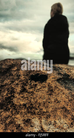 Donna in piedi sulla spiaggia in roccia Foto Stock