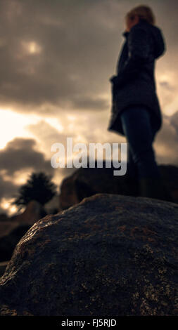 Donna in piedi sulla roccia nelle tenebre Foto Stock