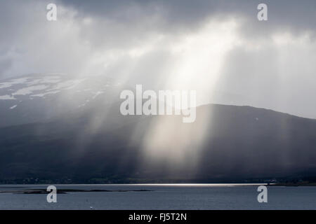 Raggi del sole attraverso il foro in nuvole, Norvegia, Troms Foto Stock
