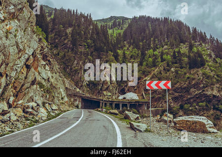 Il pittoresco paesaggio di montagna con tripla stradale chevron segno avvertenza per strada pericolosa accendere sinuose highw Transfagarasan Foto Stock