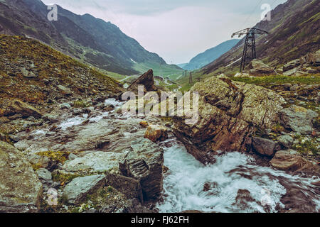 Paesaggio con ruscello di montagna rapids che scorre lungo la famosa Transfagarasan serpeggiante strada in montagna Fagaras, Romania. Foto Stock