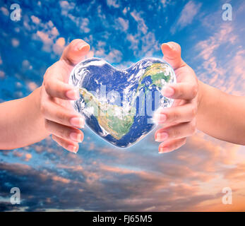 Mondo in forma di cuore con sopra le donne le mani umane su sfocato sfondo naturale: Mondo Salute del cuore giorno,Elemento di questa immagine fur Foto Stock