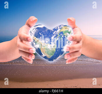 Mondo in forma di cuore con sopra le donne le mani umane su sfocato sfondo naturale: Mondo Salute del cuore giorno,Elemento di questa immagine fur Foto Stock