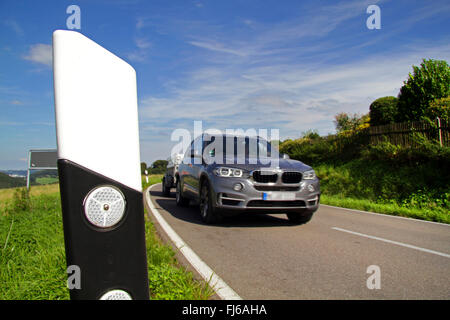 Delineatore stradale sulla banca e passaggio auto, Germania Foto Stock