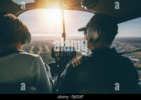 Vista interna di un elicottero in volo, con l uomo e la donna piloti vola un elicottero in una giornata di sole. Foto Stock