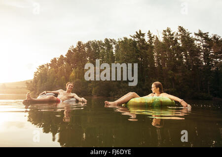 Ritratto di giovane coppia lago su anelli gonfiabile. Coppia giovane rilassante in acqua su un giorno d'estate. L uomo e la donna godendo di una d Foto Stock