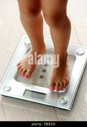 A piedi nudi donna con curatissimi toenails in piedi su una moderna elettronica di vetro bilancia da bagno come lei controlla il suo peso Foto Stock