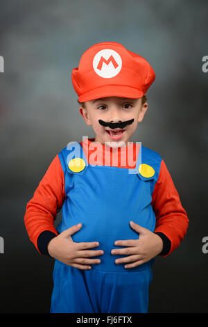 Ragazzo vestito come Super Mario Bros contro uno sfondo grigio. Foto Stock