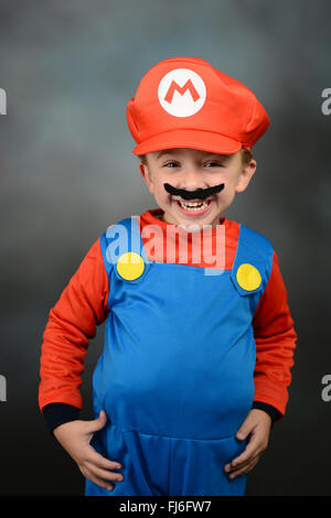 Ragazzo vestito come Super Mario Bros contro uno sfondo grigio. Foto Stock