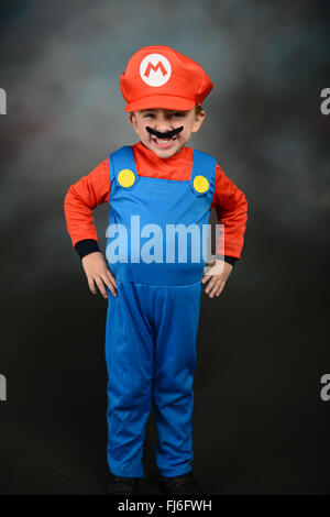 Ragazzo vestito come Super Mario Bros contro uno sfondo grigio. Foto Stock