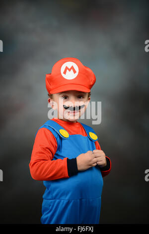 Ragazzo vestito come Super Mario Bros contro uno sfondo grigio. Foto Stock