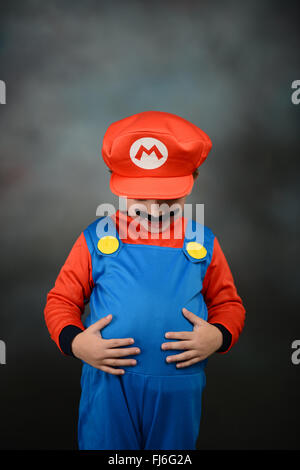 Ragazzo vestito come Super Mario Bros contro uno sfondo grigio. Foto Stock