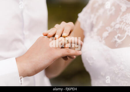 Sposa indossa un anello di nozze su lo sposo Foto Stock