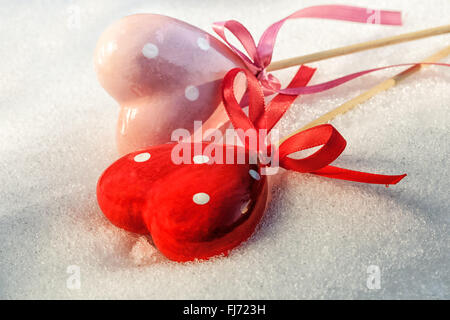 Il giorno di San Valentino, due cuori rossi su ghiaccio neve bagnata, il fuoco selettivo Foto Stock