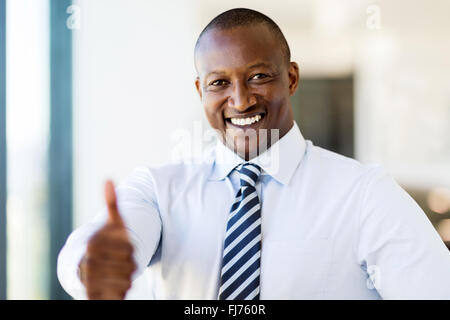 Happy business nera uomo dando il pollice in su in un ufficio moderno Foto Stock
