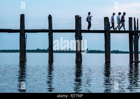 AMARAPURA, Myanmar — il ponte U Bein si estende sul lago Taungthaman vicino a Mandalay. La struttura in legno di teak lunga 1,2 chilometri, ritenuta il ponte in legno di teak più antico e più lungo del mondo, si staglia contro il cielo. Pedoni e monaci locali attraversano il ponte mentre i turisti osservano la scena iconica, particolarmente popolare durante il tramonto. Foto Stock