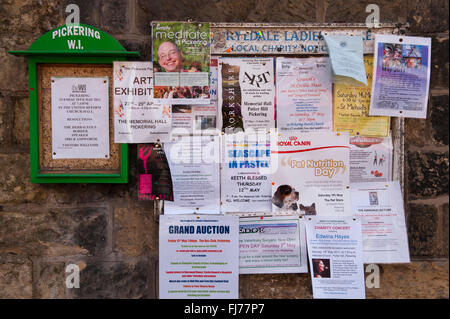 A cosa? - Close-up di avvisi (carta) imperniata al WI e comunità locale bacheca in centro città, Pickering, North Yorkshire, Inghilterra. Foto Stock