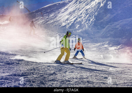 Madre e figlio sciare giù per la montagna Foto Stock