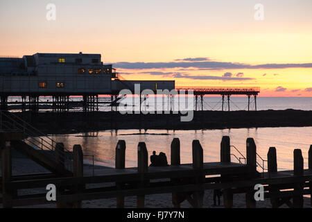 Giovane guardando la regolazione del sole,tramonto dopo la visione di storni a Aberystwyth Pier,Aberystwyth,al tramonto.Ceredigion,Galles,U.K. Foto Stock