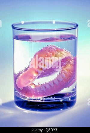 Una serie di protesi in un bicchiere con acqua Foto Stock