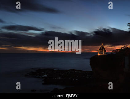 Un gazebo su una scogliera che si affaccia sull'oceano in Laguna Beach, California, illuminato con luci di Natale al tramonto. Foto Stock