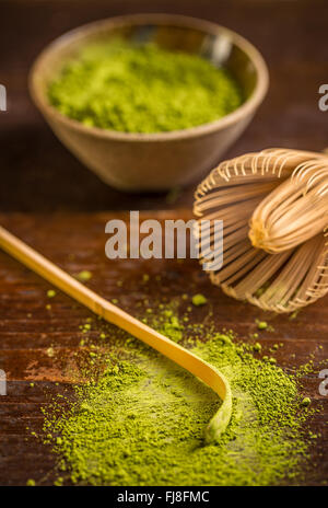 Materie verde biologico matcha tè in una ciotola con la frusta e cucchiaio Foto Stock