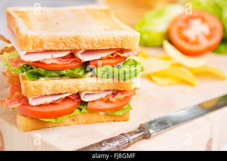 Un club sandwich su un tavolo rustico in condizioni di luce intensa. Foto Stock