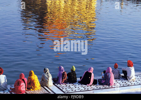 Pellegrini seduti vicino al laghetto del tempio d'oro, amritsar Punjab, India, Asia Foto Stock