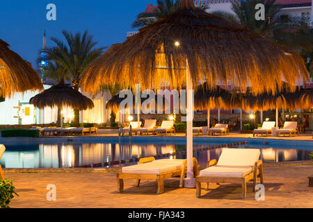 SHARM EL SHEIKH, Egitto - 27 febbraio 2014: Febbraio notte sulla spiaggia, ombrelloni di paglia e lettini in piscina presso l'hotel essere Foto Stock