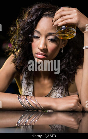 Premuto donna avente whiskey al bancone bar Foto Stock