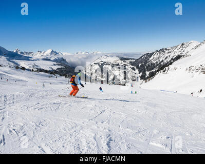 Gli sciatori sulle piste innevate in Le Grand Massif ski area sopra lo sci alpino resort di Flaine, Haute Savoie, Rhone-Alpes, Francia Foto Stock