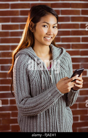 Sorridente donna asiatica utilizza lo smartphone Foto Stock