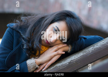 Triste giovane donna appoggiata sulle sue mani all'aperto Foto Stock