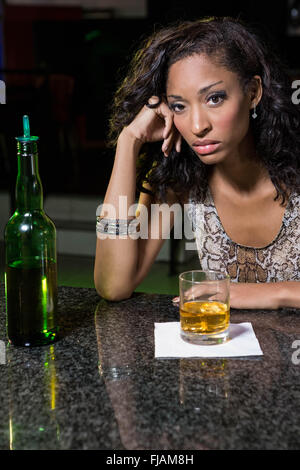 Premuto donna avente whiskey al bancone bar Foto Stock