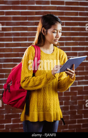 Focalizzato femmina asiatica studente utilizzando tablet Foto Stock