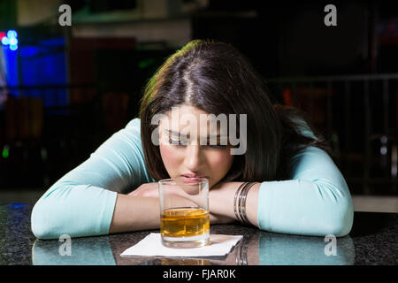 Premuto donna avente whiskey al bancone bar Foto Stock