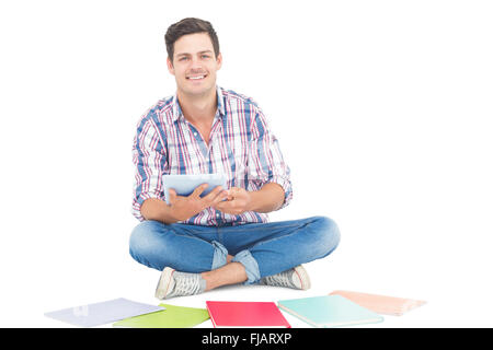 Uomo che utilizza un tablet mentre è seduto sul pavimento Foto Stock