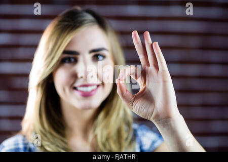 Bella donna bionda facendo segni con le dita Foto Stock