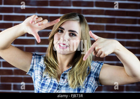 Bella donna bionda facendo segni con le dita Foto Stock