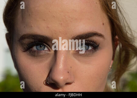 Primo piano di un bellissimo volto di donna con incredibili occhi blu e un naso forato. Foto Stock